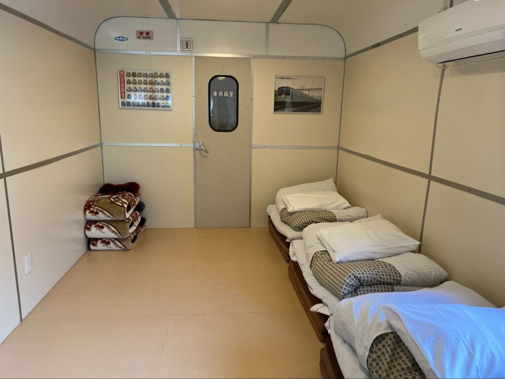 都留市の宿ぽっぽやにある鉄道車両風の客室と布団が並ぶ室内 