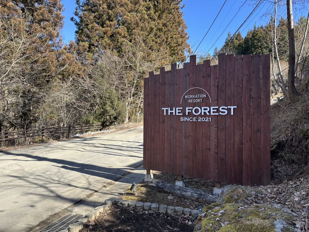 山梨県都留市のグランピング施設「THE FOREST」の入口に立つ木製の看板